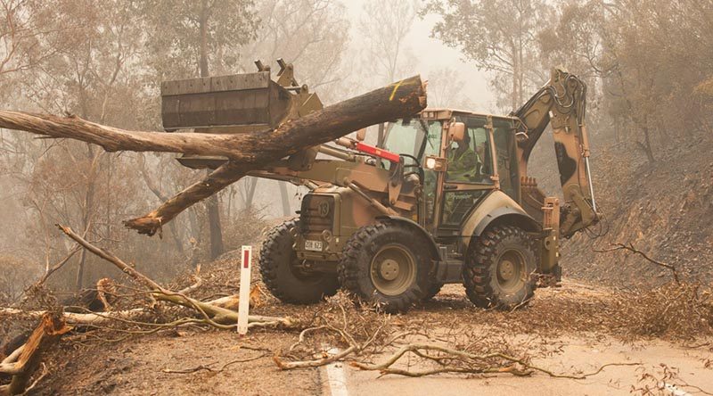 Plant operators Cpl Duncan Keith and Sapper Ian Larner of the 22nd Engineer Regiment use a 434 backhoe to assist staff from Forestry Management Victoria to clear fire-damaged trees from the Great Alpine Road between Bairnsdale and Omeo during Operation Bushfire Assist 19-20. Photo by Private Michael Currie.