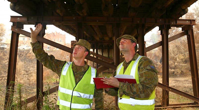 Army sappers Lance Corporal Rick Williams, left, and Corporal Ross Lorenz, of the 5th Engineer Regiment, inspect a fire-damaged bridge in Cobargo. Photo by Sergeant Max Bree.