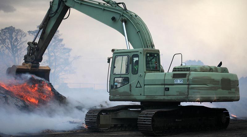 Sapper Mathias Beddie, 2nd Combat Engineer Task Group – NSW, pulls-down piles of burning mulch so that bulldozers and graders may spread it for firefighters to extinguish with water. The piles are too dense to extinguish without first being spread and could otherwise smoulder for weeks and remain a fire hazard. Photo by Major Cameron Jamieson.