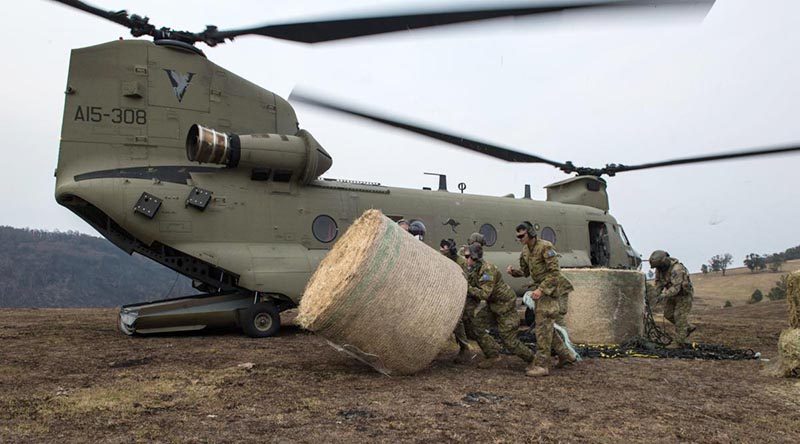 Soldiers from the 7th Battalion, the Royal Australian Regiment, move a bale of hay for livestock delivered by an Australian Army CH-47F Chinook near Jackson’s Crossing, Victoria: Photo by Private Michael Currie.