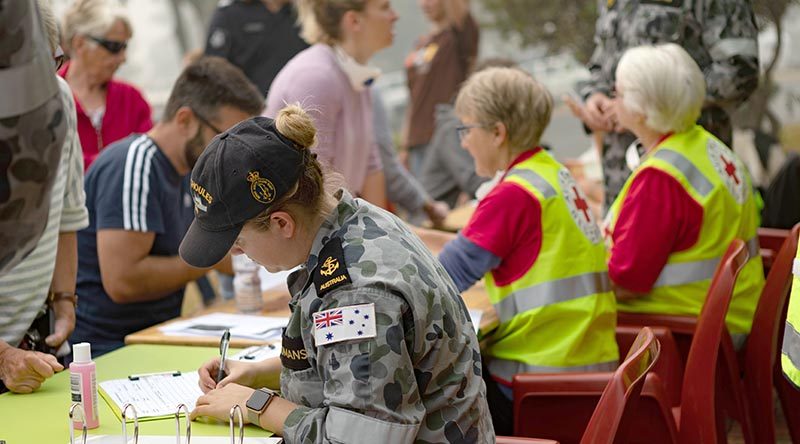 Leading Seaman Medic Abbey-Rose Yeoman and Red Cross volunteers fill out evacuation registration forms for the Mallacoota residents. Photo by Leading Seaman Shane Cameron.