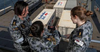 Petty Officer Helen Frank, centre, shows Leading Seaman Afton Mitchell, left, and Able Seaman Liliana Kleber a photo of how close the fire-front was to her parent's property in Orbost, Victoria. Photo: Leading Seaman Shane Cameron.