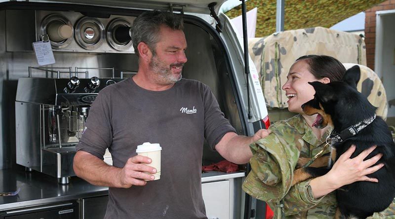 Ged Gross delivers the coffee while his Kelpie pup Tuna delivers the smiles for Captain Alisha Reeves in Bega. Photo by Major Cameron Jamieson.