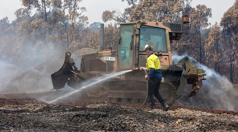 An Australian Army Combat Engineer from the 5th Engineer Regiment uses a JD-450 Bulldozer to spread burnt woodchips at the Eden Woodchip Mill in southern NSW in support of Operation Bushfire Assist 19-20. Photo by Sergeant Max Bree.