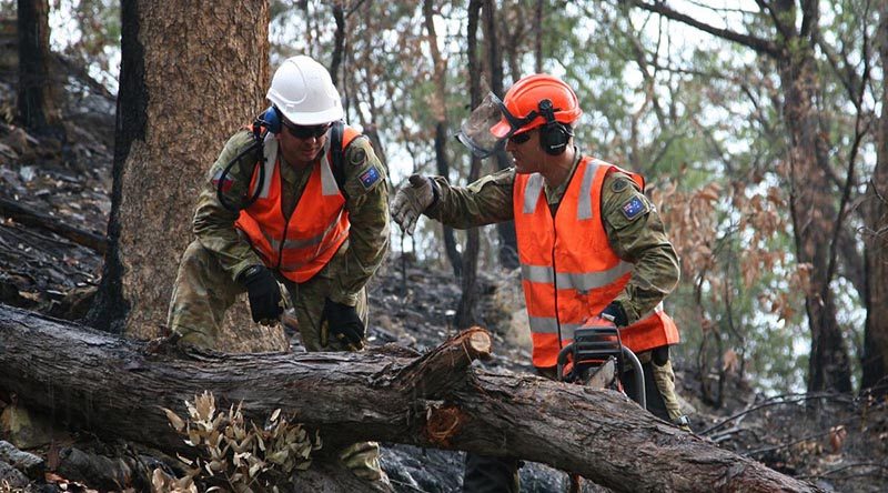 Sapper Tim Daniels, right, discusses with Sapper Aemon Kelly the best way of cross-cutting a fallen tree blocking Commission Road in Wollemi National Park south of Bulga, NSW. Photo by Major Cameron Jamieson.