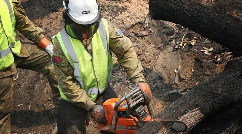 Gunner Kyle Moore, an artilleryman from 7 Field Regiment, crosscuts a fallen tree resting on a road at Lower Bago, south of Tumut, NSW. He is trained in chainsaw operations to make gun pits for the artillery, and is putting his skills to work helping the combat engineers from the Brisbane-based 2nd Combat Engineer Regiment during Operation Bushfire Assist 19-20. Photo by Major Cameron Jamieson.