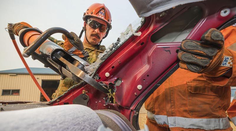 Private Andrew Cuttler, of the 5th/6th Royal Victorian Regiment, helps a State Emergency Service volunteer use the 'jaws of life' during training at the Bright SES depot. Photo by Corporal Sebastian Beurich.