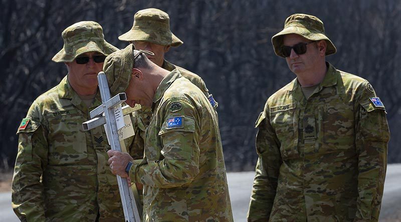 Lieutenant Kynan Lang from the 10th/27th Battalion, RSAR, is supported by colleagues at the place where his uncle and cousin died in a bushfire on Kangaroo, before placing a memorial in their honour. Photo by Corporal Tristan Kennedy.