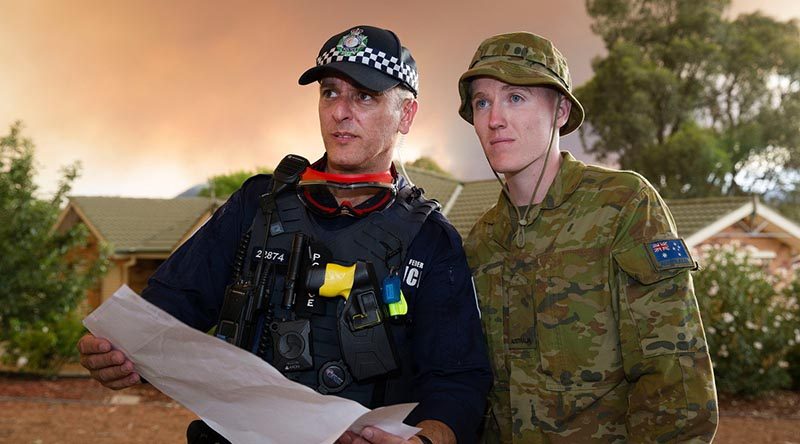 Australian Army soldier Private Lleyton Jones and Australian Capital Territory policeman Constable Marko Banic about to begin door knocking homes in Canberra’s southern suburbs to advise residents on the status of the Orroral Valey fire burning in the Namadgi National Park. Photo by Sergeant Max Bree.