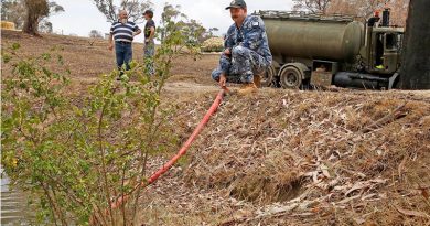 Air Force Leading Aircraftman Corrie Street, of No. 65 Squadron, RAAF Base Richmond, offloads 15,000 litres of much-needed water to farmer Rod Daisley of Tumbarumba, New South Wales, while Mr Daisley and Leading Aircraftwoman Tiane Westland, chat in the background. Photo by Sergeant Dave Morley.