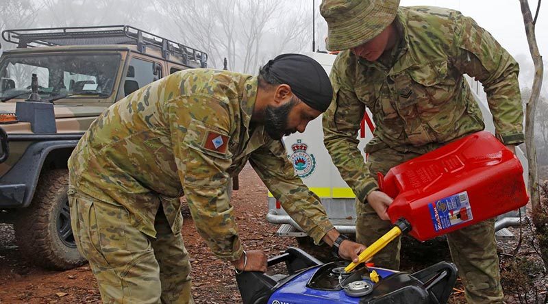 Private Manpreet Singh and Corporal Luke Ford of the Brisbane-based 7th Combat Services Support Battalion refuel a generator that powers a remote and vital RFS radio-relay antenna. Photo by Sergeant Dave Morley.