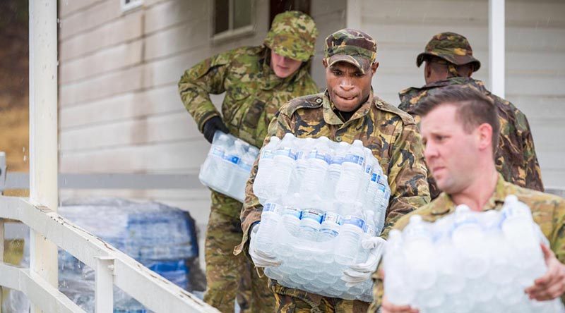 Papua New Guinea Defence Force sapper Moses Wai helps Australian Army soldiers move water at the Benambra Recreation Area. Photo by Corporal Sebastian Beurich.