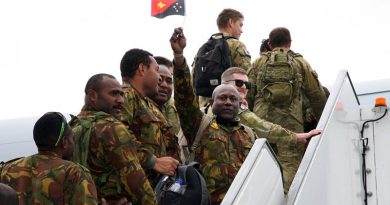 A Papua New Guinea Defence Force soldier proudly waves his nation’s flag as he and fellow Task Group Dingo members board a Royal Australian Air Force KC-30 Multi-Role Tanker Transport aircraft at Tullamarine Airport on their way home. Photo by Major Cameron Jamieson.