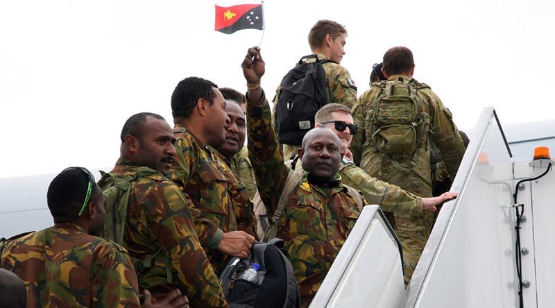 A Papua New Guinea Defence Force soldier proudly waves his nation’s flag as he and fellow Task Group Dingo members board a Royal Australian Air Force KC-30 Multi-Role Tanker Transport aircraft at Tullamarine Airport on their way home. Photo by Major Cameron Jamieson.