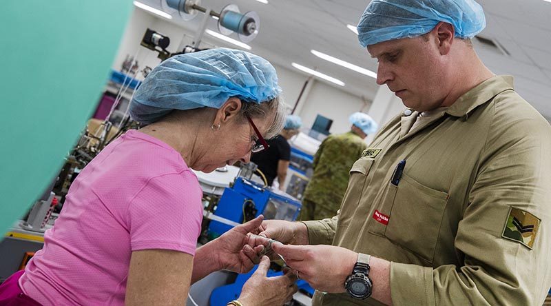 Australian Army soldier Corporal Sander Vloothuis and Med-Con employee Lynn Stockwell inspect a surgical face mask off the production line. Photo by Corporal Sagi Biderman.