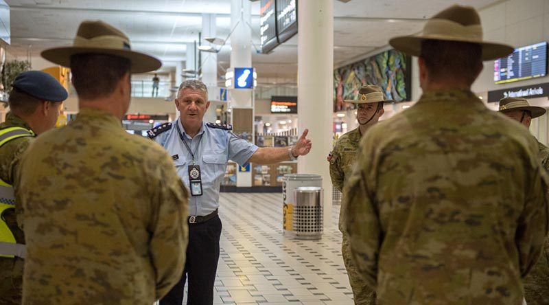 Inspector Peter Aitken from the Queensland Police Service briefs an Australian Army contingent from the 9th Battalion, Royal Queensland Regiment, supporting mandatory COVID-19 quarantine arrangements for international travellers at Brisbane Airport. Photo by Trooper Jonathan Goedhart.