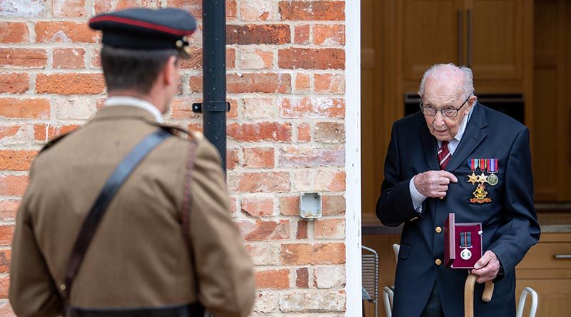 Colonel Tom Moore talks to Lieutenant Colonel Thomas Miller while holding The Yorkshire Regiment Medal, re-presented as a birthday gift from the British Army after he lost the original. Photo by Corporal Robert Weideman, UK Ministry of Defence.