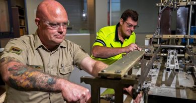 Australian Army soldier Sergeant Steven Davidson assists Bob Neighbour to repair a medical mask manufacturing machine at Med-Con Pty Ltd. Photo by Corporal Sagi Biderman.