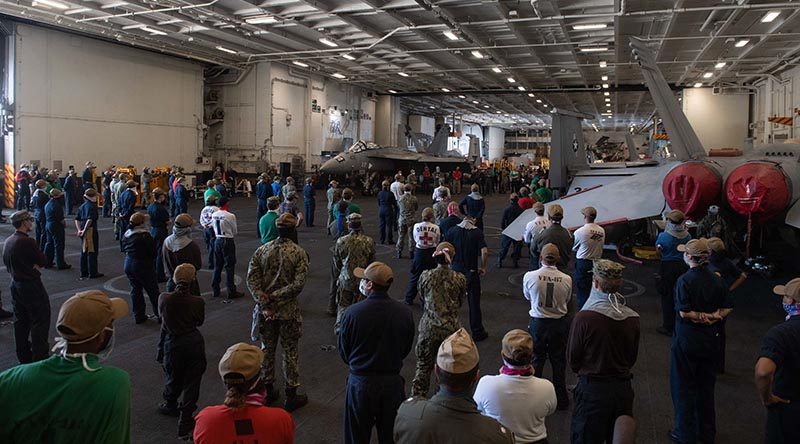 Crew of the USS Theodore Roosevelt listen to Vice Admiral William Merz, commander US 7th Fleet, answering questions during a visit to the ship on 7 April 2020. US Navy photo by Mass Communication Specialist Seaman Kaylianna Genier.