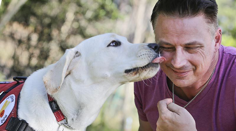 Former Australian infantryman Andrew Glebow gets a 'kiss' from his new assistance dog Leon in his back yard at Shailer Park, Brisbane.