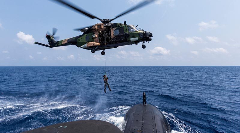 A Royal Australian Navy sailor is lowered to the casing of HMAS Collins from an MRH-90 helicopter in the Bay of Bengal during AUSINDEX 2019. Photo by Leading Seaman Jake Badior.