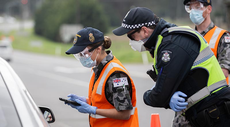 Royal Australian Navy Seaman Kirie South, from HMAS Cerberus, checks a driver’s details at a vehicle control point in Victoria, assisting the Victoria Police Force during Op COVID-19 Assist. Photo by Leading Aircraftman John Solomon.