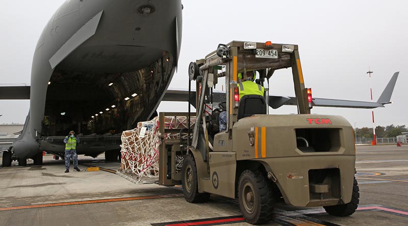 Aircraftman Joseph Freeman directs forklift driver Leading Aircraftman Christopher Wettenhall from No. 23 Squadron, during the physical loading of virtual conferencing systems onto a No. 36 Squadron C-17A Globemaster III bound for Fiji. Photo by Corporal Colin Dadd.