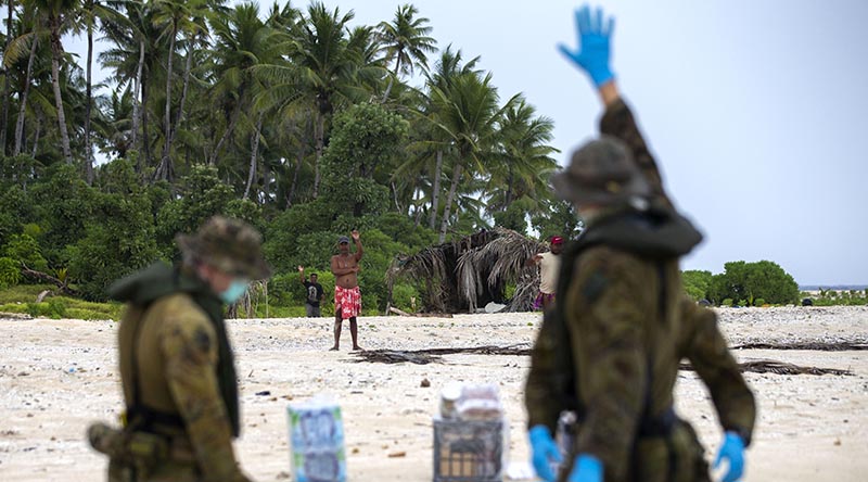 Australian soldiers from 2RAR, keeping their distance because of COVID-19, deliver supplies to three Micronesian mariners stranded on a small island awaiting rescue. Photo by Leading Seaman Kieren Whiteley.