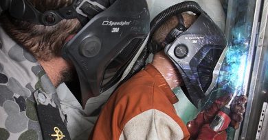 Royal Australian Navy sailor Leading Seaman Cameron Campbell supervises Able Seaman Matthew Gates in a welding task. Photo by Petty Officer James Whittle, digitally enhanced by CONTACT (adding extra weld sparkles).