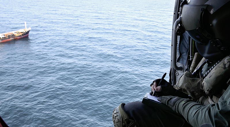 Leading Seaman Aircrewman Brad Firkin collects information on a vessel of interest from HMAS Arunta's MH-60R Seahawk helicopter during Operation Argos. Photo by Leading Seaman Jarrod Mulvihill.