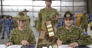 Outgoing Commander of Joint Task Force 633 Major General Susan Coyle and her replacement, Rear Admiral Michael Rothwell sign the papers to transfer command of Australian forces in the Middle East, watched by incoming Command Warrant Officer WO1 Mark Retallick. Photo by Sergeant Ben Dempster.