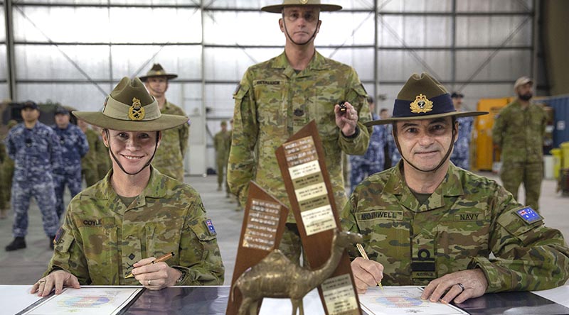 Outgoing Commander of Joint Task Force 633 Major General Susan Coyle and her replacement, Rear Admiral Michael Rothwell sign the papers to transfer command of Australian forces in the Middle East, watched by incoming Command Warrant Officer WO1 Mark Retallick. Photo by Sergeant Ben Dempster.