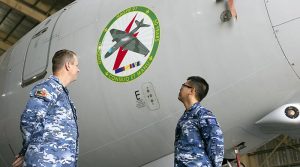 Sergeant Nathan Bradford and Leading Aircraftsman Sam Chan with the nose-art design they completed on an E-7A Wedgetail in the Middle East. Photo by Corporal Tristan Kennedy.
