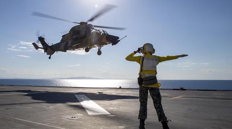 Able Seaman Lily Hardin waves off an Army ARH-Tiger as it takes off from the deck of HMAS Adelaide near Townsville during Exercise Sea Wader. Photo by Leading Seaman Nadav Harel.