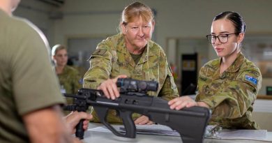 Warrant Officer Class 2 Cheryl Peebles, centre, with a soldier signing out a weapon from the armoury at Camp Baird in the Middle East region. Photo by Corporal Tristan Kennedy.