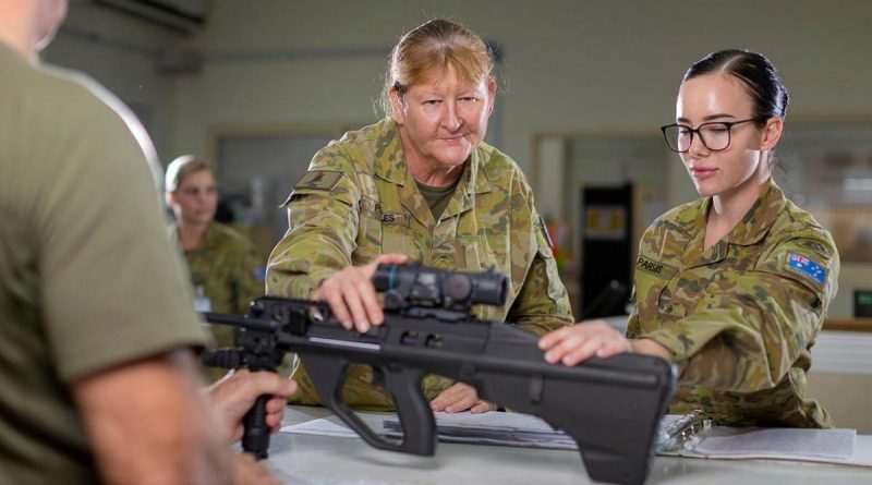 Warrant Officer Class 2 Cheryl Peebles, centre, with a soldier signing out a weapon from the armoury at Camp Baird in the Middle East region. Photo by Corporal Tristan Kennedy.