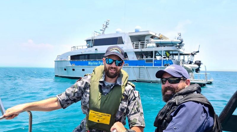 ADV Cape Inscription Navigation Officer Lieutenant Rhys Worboys and Great Barrier Reef Marine Park Authority officer Dwaine Butcher in front of Reef Ranger, a Queensland Parks and Wildlife Service vessel.