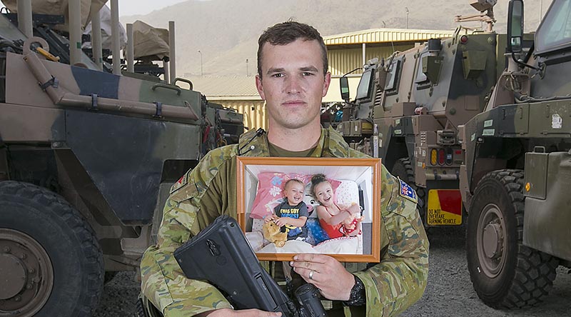 Private Kieren Morrissey, from Dubbo, deployed with Force Protection Element 10 on Operation Highroad in Kabul, Afghanistan, holds a photo of his children Aria and Sloane, on Father's Day 2018. Photo by Petty Officer Andrew Daken.