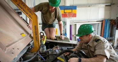 Lance Corporal Cameron Pennell, left, and Rear Admiral Michael Rothwell begin removing the engine from a protected mobility vehicle in the Middle East region. Photo by Sergeant Ben Dempster.