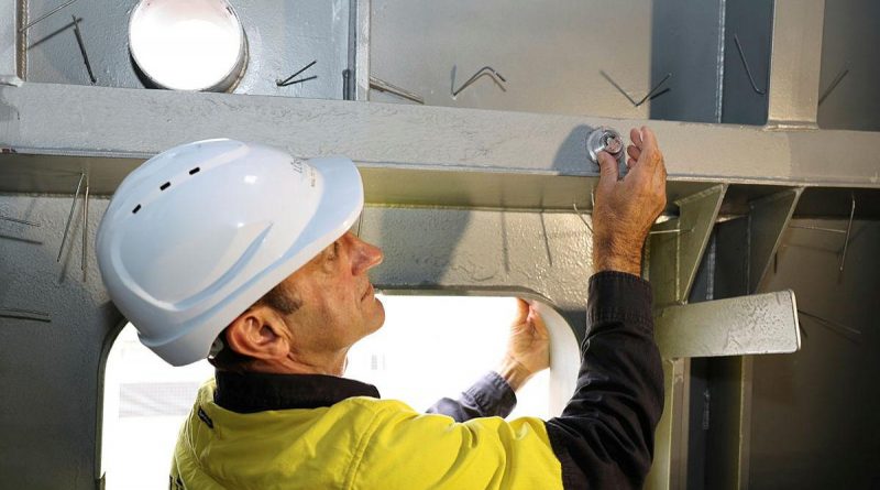 Luerssen Australia shipbuilder Malte Hoffman secures a coin inside the mast of the offshore patrol vessel Arafura in a mast-stepping ceremony held at Osborne Shipyard in South Australia.