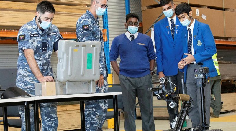 Leading Aircraftman Chris Carrigan, left, and Leading Aircraftman Jordan Hopkins demonstrate a vehicle used to detect Improvised Explosive Devices to Patrician Brothers students Amarjith Ajith, Agam Gujral and Damien Sinha, Photo by Corporal Kylie Gibson.