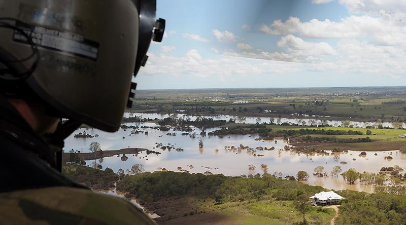 A helicopter loadmaster surveys floodwaters near Bundaberg, Queensland (2013). Photograph by Corporal Janine Fabre.