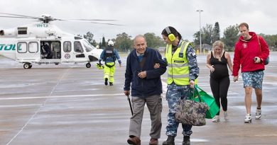 Leading Aircraftwoman Leah McDonald, from No. 22 Squadron, assists evacuee Ian Clucas at RAAF Base Richmond. Photo by Corporal Kylie Gibson.