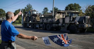 Darcy Elbourne waves the Australian flag in the driveway of his home as Army personnel head out to conduct relief and recovery tasks during Operation NSW Flood Assist in Taree. Photo by Corporal Sagi Biderman.