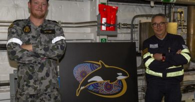 Leading Seaman Jackson Setter, left and Navantia Australia engineer Jose Luis Bouza Fernandez stand with a new passageway sign for HMAS Supply. Story by Lieutenant Jessica Craig. Photo by Able Seaman Benjamin Ricketts.