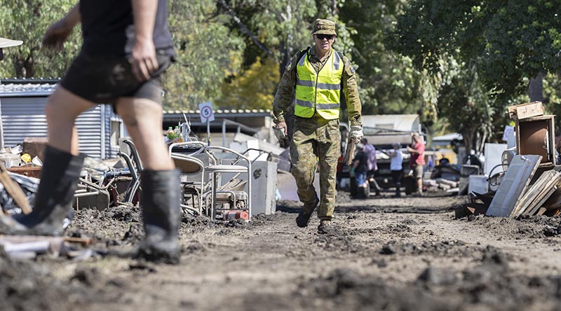 An Australian Army soldier deployed on Operation NSW Flood Assist walks between debris from flood damage in Wisemans Ferry, New South Wales. Photo by Corporal Sagi Biederman.