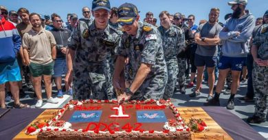 HMAS Sydney's youngest crew member Seaman Sebastien Schultz, left, and Commanding Officer Commander Edward Seymour cut a cake to mark the first anniversary of the ship's commissioning into the Navy. Story by Lieutenant Sarah Rohweder.