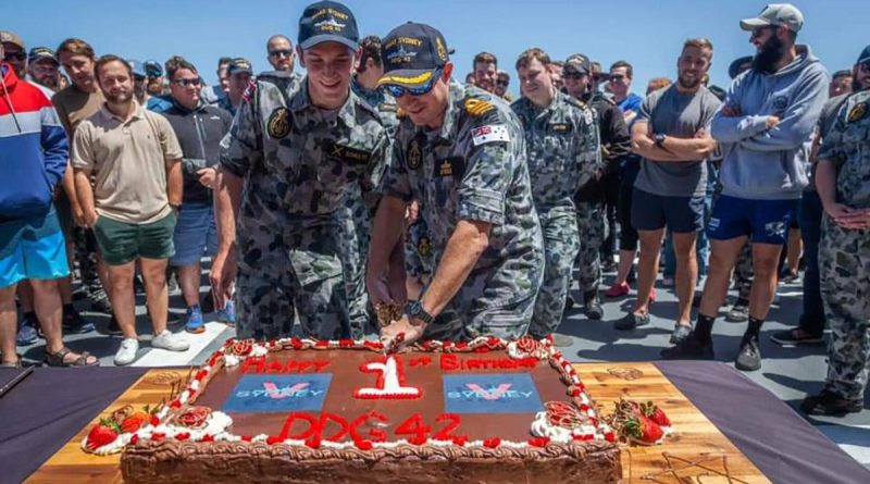 HMAS Sydney's youngest crew member Seaman Sebastien Schultz, left, and Commanding Officer Commander Edward Seymour cut a cake to mark the first anniversary of the ship's commissioning into the Navy. Story by Lieutenant Sarah Rohweder.