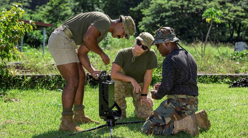 Private Osama Ahmed, left, Lieutenant Amy Rowlings and Vanuatu Police Maritime Wing Constable Sione Motoutorua connect the antenna to the Epi Island’s Police Post radio mast. Story by Corporal Olivia Cameron. Photo by Corporal Olivia Cameron.