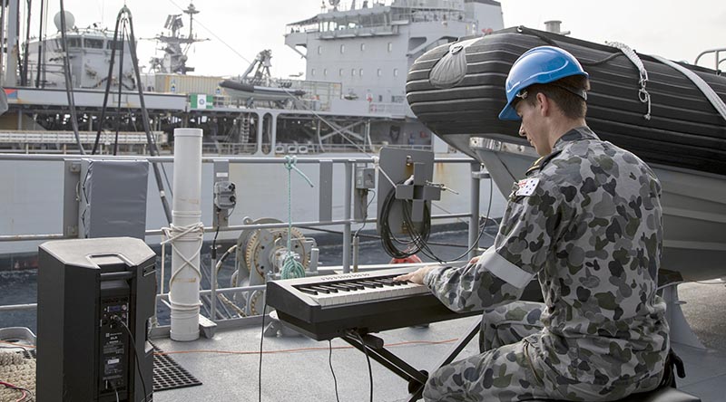 Able Seaman Xavier Riddell plays a tune for HMAS Sirius during a replenishment at sea in the Bay of Bengal. Photo by Leading Seaman Thomas Sawtell.